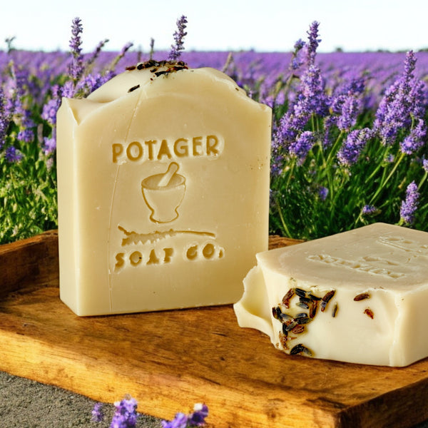 Two bars of soap on a wooden board with lavender in the background