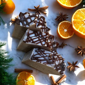 Cinnamon drizzled soap bars on a marble surface with oranges and star anise around.