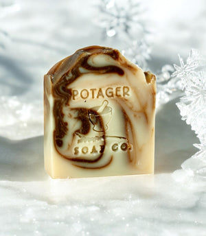 Marbled soap bar with 'Potager Soap Co.' branding on a snowy background