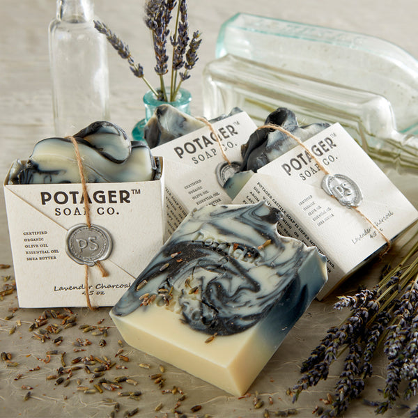 Marble-patterned lavender charcoal soaps by Potager Soap Co. with lavender and a vintage glass bottles in the background.