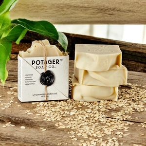 Bar of soap with packaging from Potager Soap Co. on a wooden surface with oats.