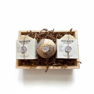Potager Soap Co. artisan soap gift set featuring two organic soap bars and a bath bomb in a rustic wooden crate.