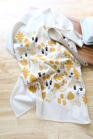 Potager Soap Co. handprinted cotton kitchen towel with golden ochre leaves and chocolate brown acorns on cream fabric.