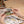 Potager Soap Co. DIY book nook kit assembly showing hands using tweezers to place a miniature floral arrangement.