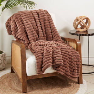Potager Soap Co. brown faux rabbit fur throw blanket with ribbed texture draped over a wooden armchair