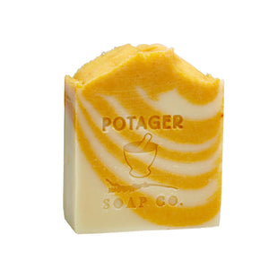 Potager Soap Co. artisan bar soap with orange and white swirls and embossed logo on a white background.