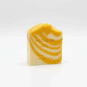 Potager Soap Co. artisan bar soap with orange and white swirls and embossed logo on a clean white background.