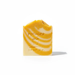 Potager Soap Co. artisan bar soap with a vibrant orange and creamy white swirl design and embossed logo.