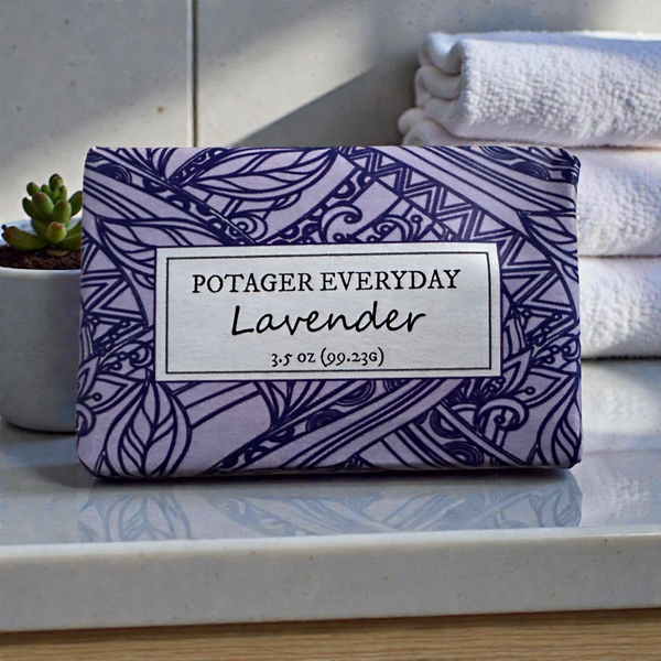 Potager Soap Co. Everyday Lavender bar soap in purple patterned paper packaging on a bathroom counter with towels.