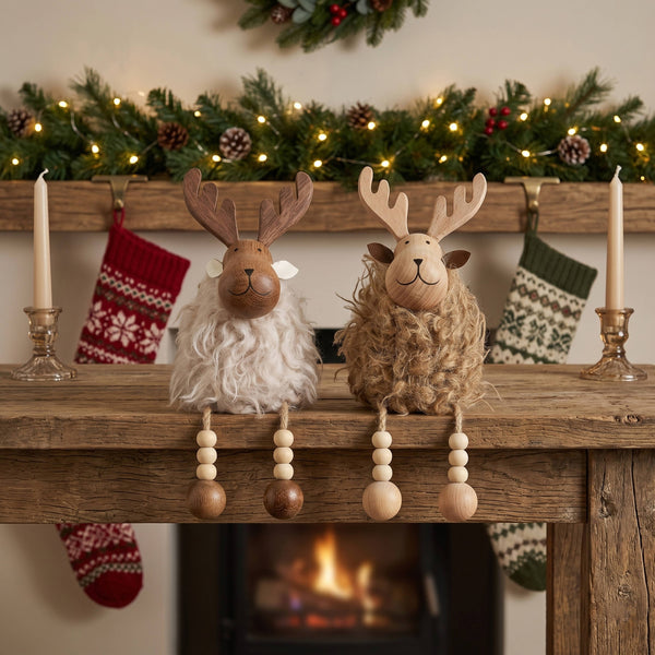Potager Soap Co. pair of rustic reindeer ornaments with carved wood heads and faux fur bodies on a wooden mantelpiece.