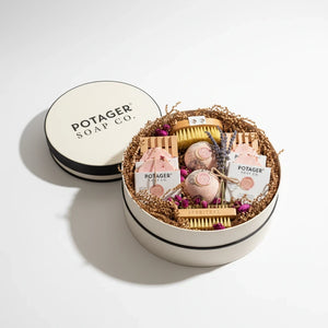 Potager Soap Co. handcrafted gift set in a white linen hat box with soaps, bath bombs, and brushes on paper filler.