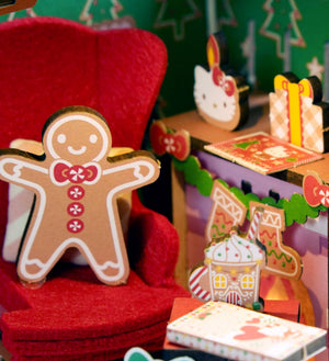Potager Soap Co. Hello Kitty wooden gingerbread man figurine sitting on a red felt chair with festive holiday decor