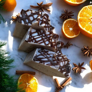 Potager Soap Co. Holiday Spice organic bar soap with dark swirls, surrounded by fresh orange slices and spices.