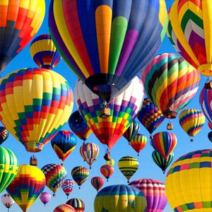 Potager Soap Co. wooden jigsaw puzzle featuring a vibrant sky filled with colorful hot air balloons in flight.
