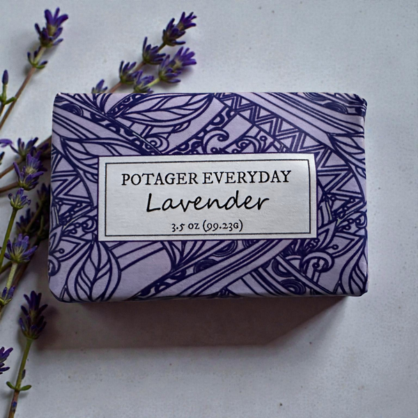 Potager Soap Co. Everyday Lavender bar soap wrapped in purple paper with botanical patterns next to lavender sprigs.