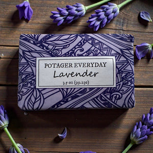 Potager Soap Co. Everyday Lavender bar soap in purple patterned paper packaging surrounded by fresh lavender sprigs.