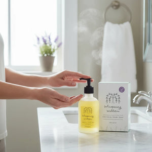Potager Soap Co. Whispering Willow lavender hand soap in a glass pump bottle with its matching box on a bathroom vanity.
