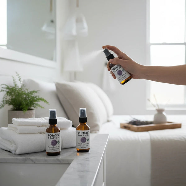 Hand spraying Potager Soap Co. French Lavender organic room and linen spray in a bright, serene bedroom setting.