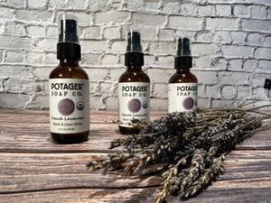 Three Potager Soap Co. amber glass bottles of organic French Lavender room and linen spray with dried lavender stems.