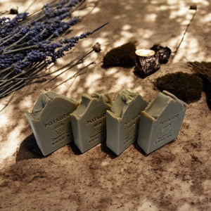 Potager Soap Co. lavender and patchouli botanical bar soaps with rustic texture on a sandy surface with dried lavender.