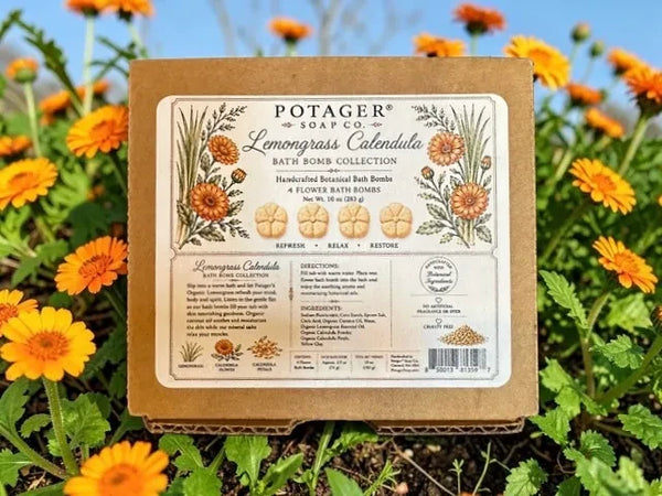 Potager Soap Co. Lemongrass Calendula bath bomb box set surrounded by vibrant orange calendula flowers in a garden.