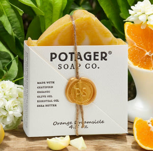 Potager Soap Co. Orange Creamsicle artisan soap bar in white paper packaging with a gold wax seal on a wooden surface.