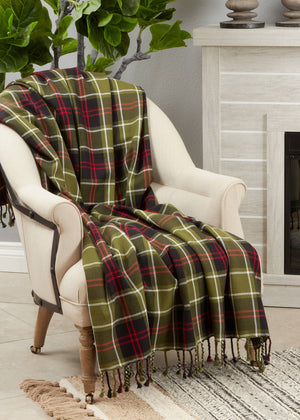 Potager Soap Co. cotton throw blanket in olive green, black, and red plaid draped over a cream armchair.