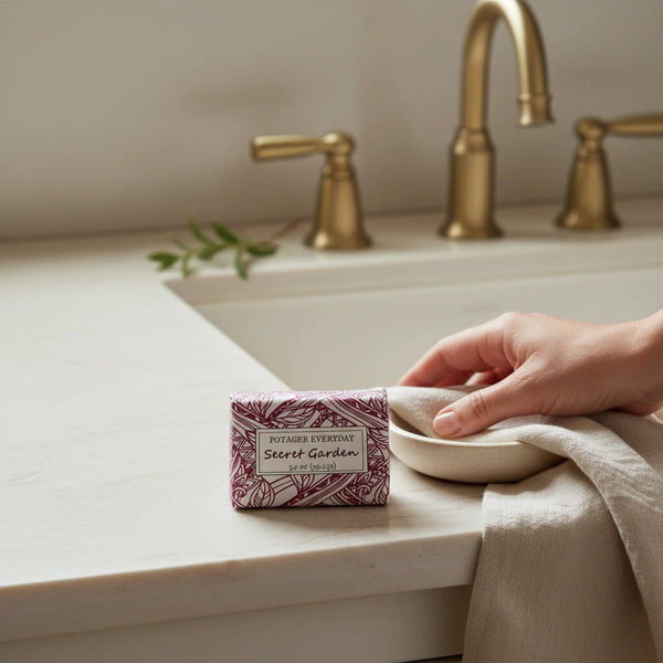 Potager Soap Co. Secret Garden bar soap in botanical-patterned paper packaging sitting on a marble bathroom vanity.