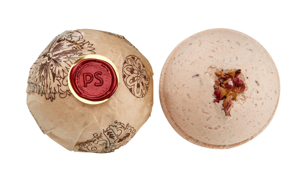 Potager Soap Co. Secret Garden bath bomb wrapped in paper with a wax seal next to an unwrapped rose petal bath bomb.