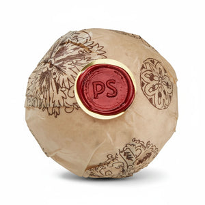 Potager Soap Co. Secret Garden bath bomb wrapped in brown paper with a red wax seal featuring the PS logo.