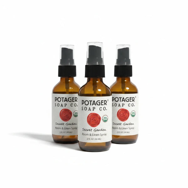 Three Potager Soap Co. Secret Garden room and linen spray bottles in amber glass with black spray nozzles.