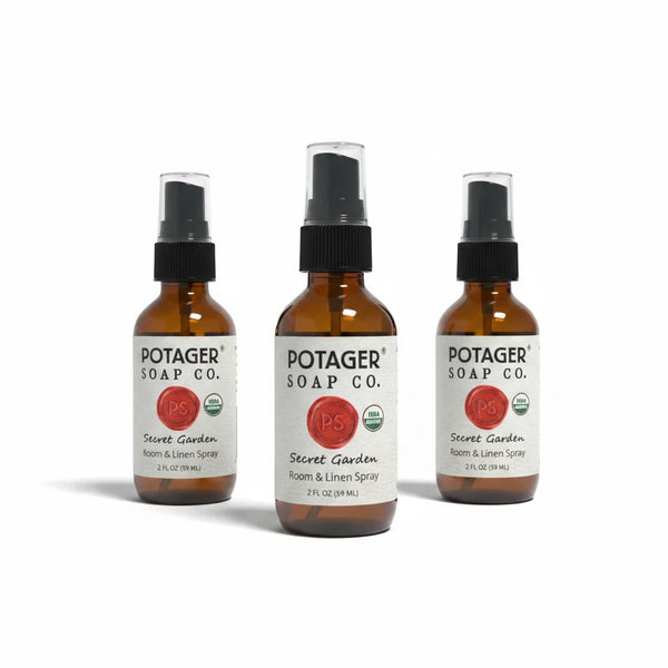 Three Potager Soap Co. Secret Garden room and linen spray bottles in amber glass with black spray nozzles.