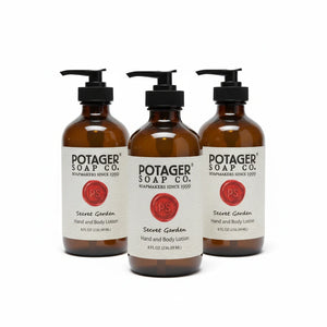Three amber glass bottles of Potager Soap Co. Secret Garden Hand and Body Lotion with black pump dispensers