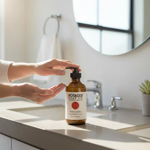 Potager Soap Co. Secret Garden hand and body lotion in an amber glass bottle with a pump on a bathroom vanity.