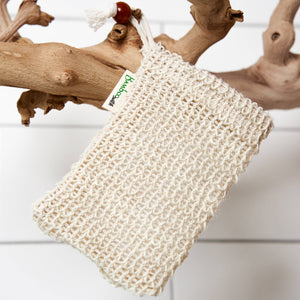 Potager Soap Co. BambooSwitch sisal exfoliating soap saver bag with drawstring and wooden bead hanging on driftwood.